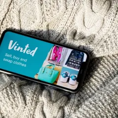 Telefon z aplikacją Vinted na tle dzianinowego swetra.