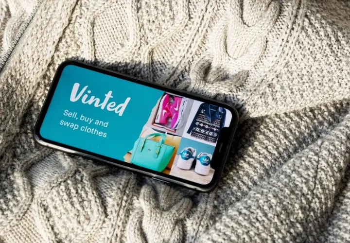 Telefon z aplikacją Vinted na tle dzianinowego swetra.